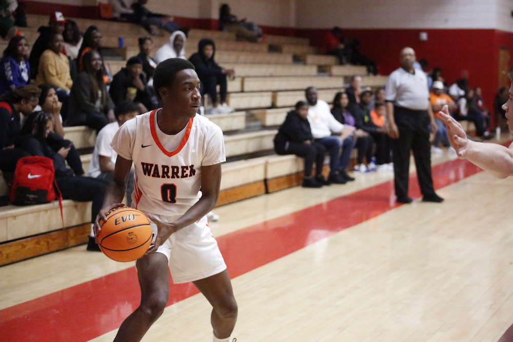 A young man holding a basketball in front of an audience.