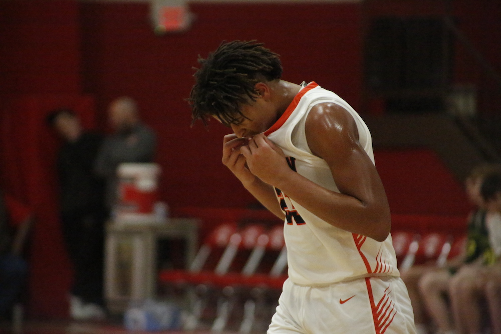 A basketball player is holding his head down.