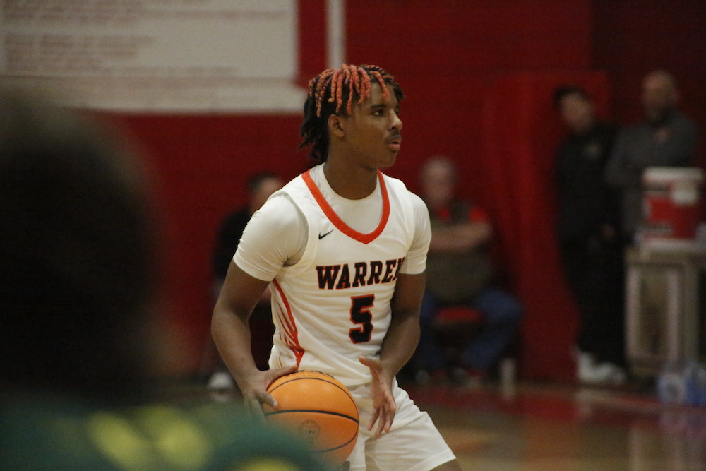 A young man holding onto a basketball in front of him.