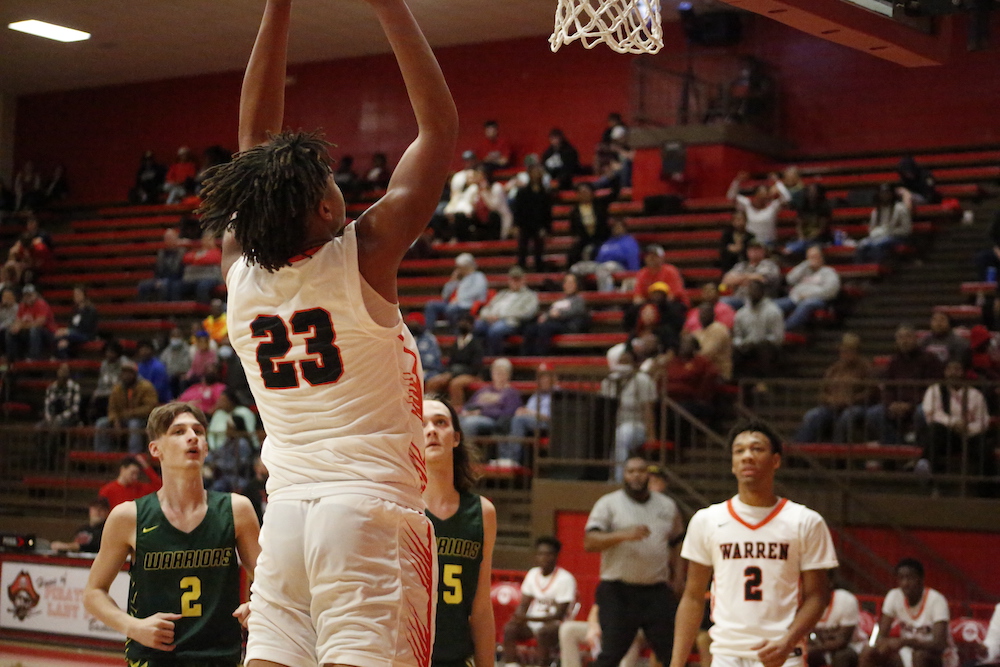 A basketball player is jumping up to dunk the ball.