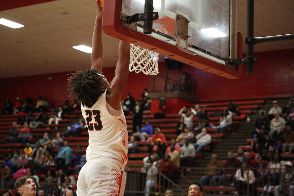 A man that is jumping in the air with a basketball.