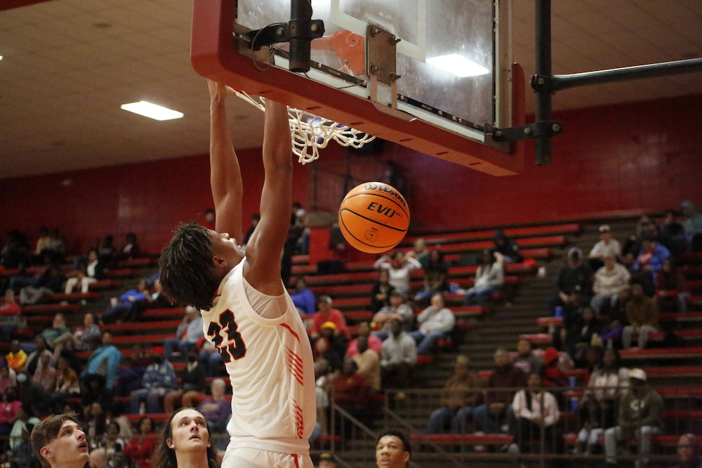 A man that is jumping in the air with a basketball.