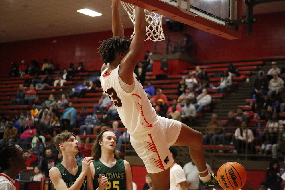 A man that is jumping in the air with a basketball.