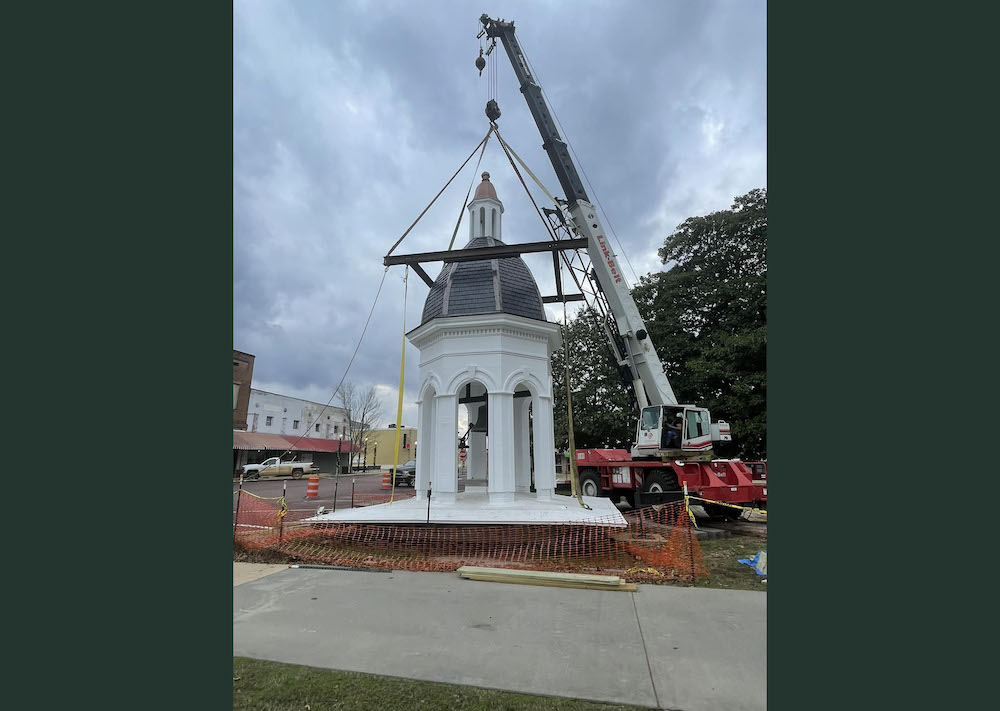 A crane is lifting the top of a building.