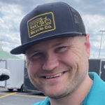 A man wearing a hat and smiling for the camera.