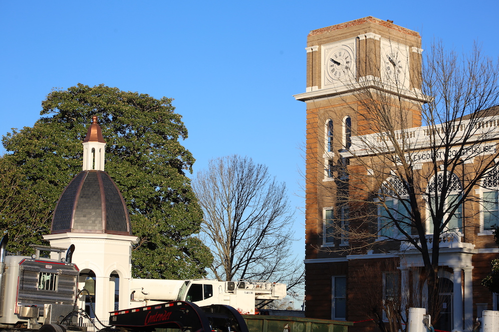 A tractor parked in front of a building with a clock tower.