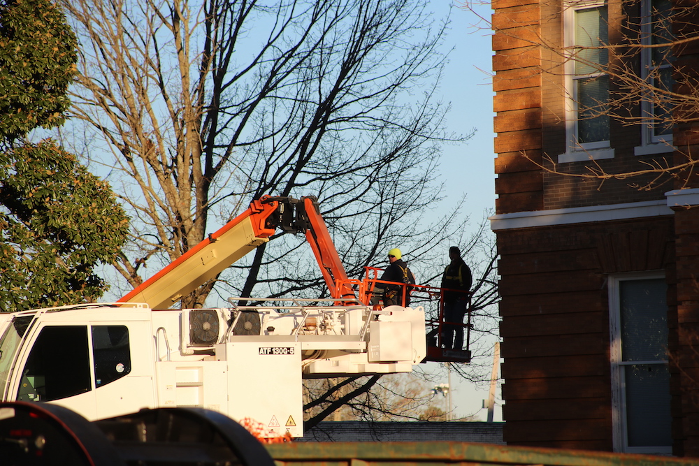 A crane is being used to remove trees from the roof of a building.