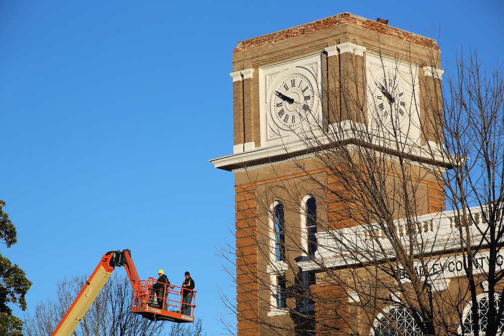 Two men in a cherry-picker working on the clock tower.