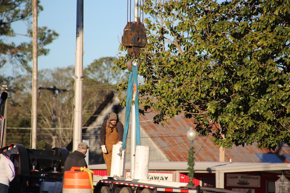 A crane is being used to lift a light pole.