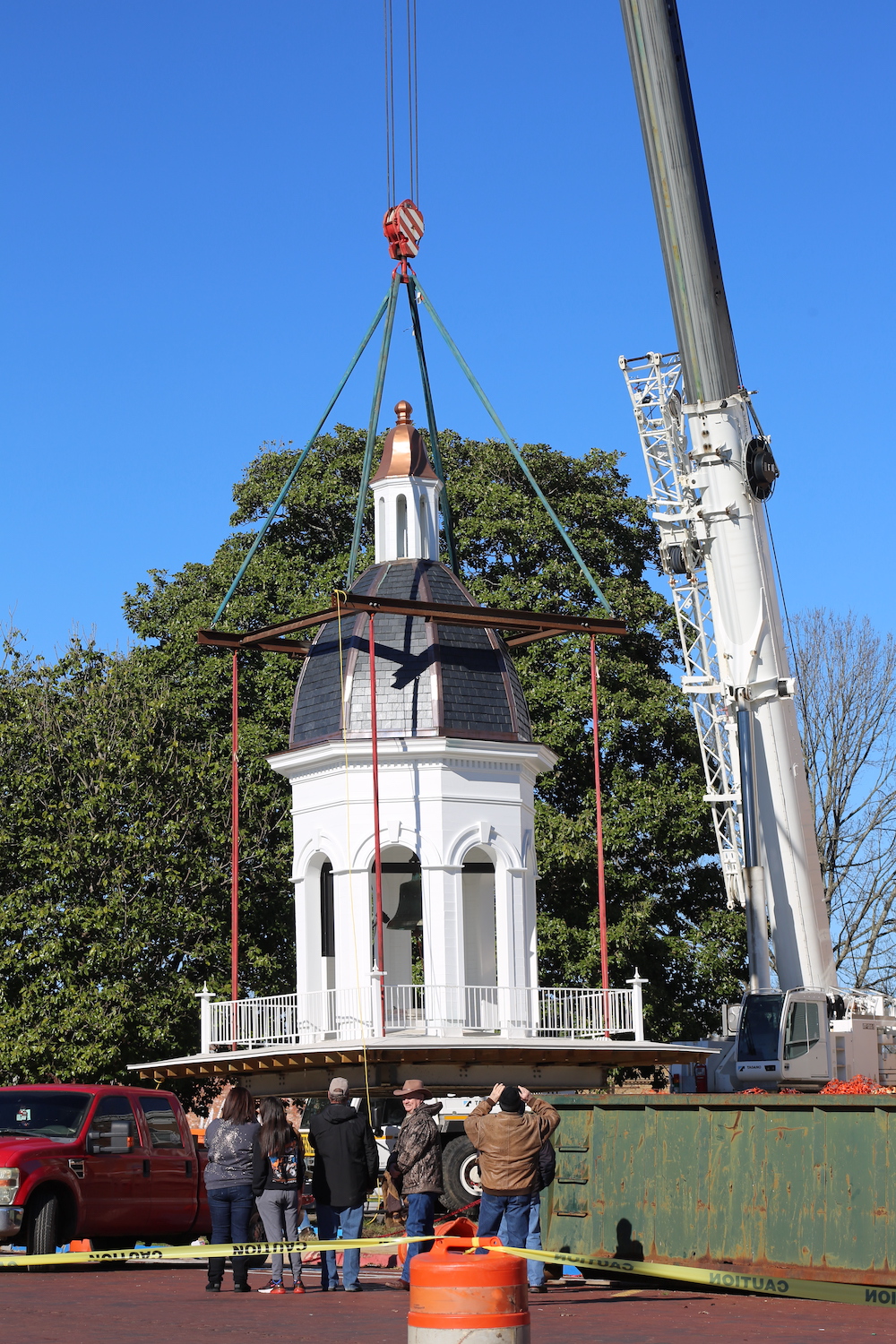 A crane is lifting the gazebo off of the ground.
