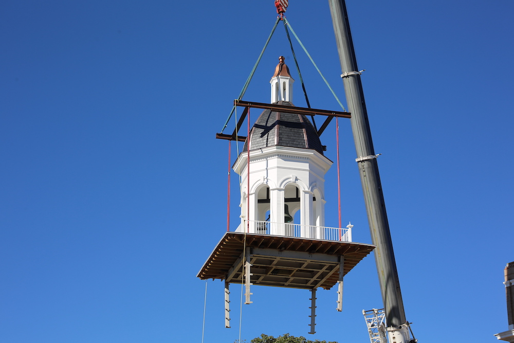 A crane is lifting a white and black building