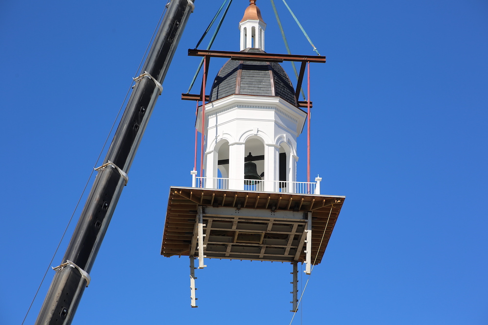 A crane is lifting a bell tower into place.