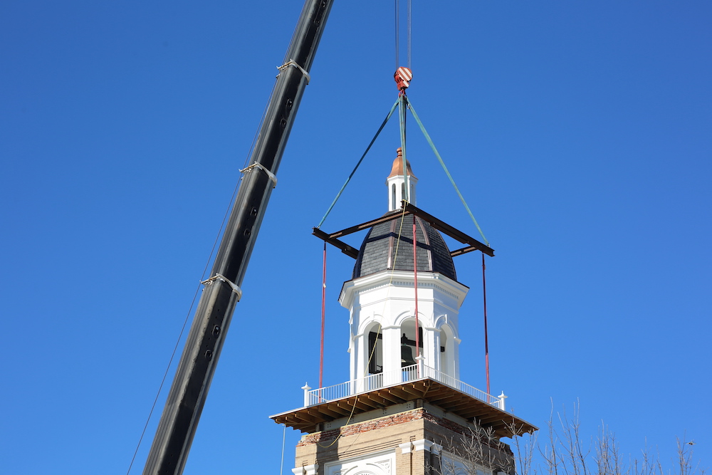 A crane is lifting the top of a building.