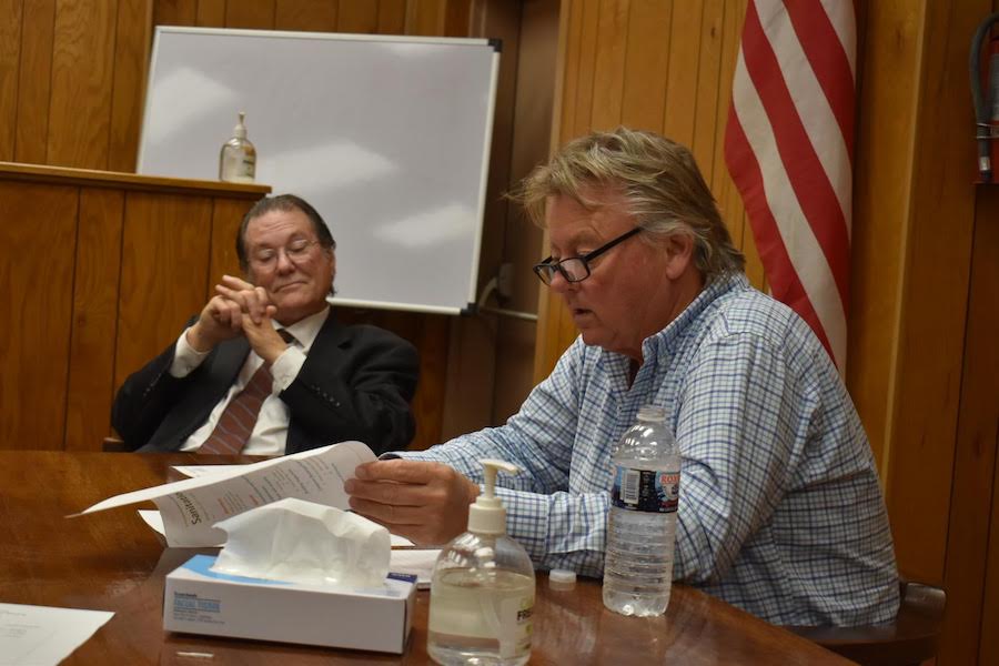 Two men sitting at a table with papers.