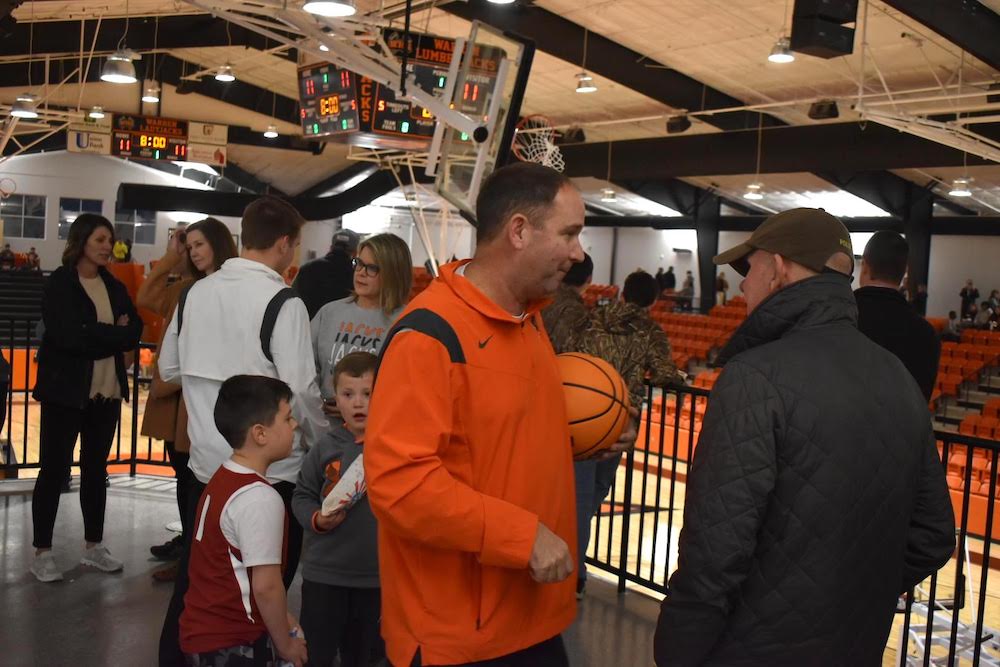 A man holding a basketball in front of people.