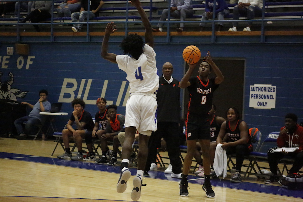 A couple of men playing basketball on a court.