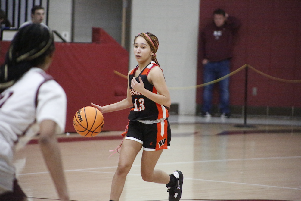 A girl dribbles the basketball on a court.