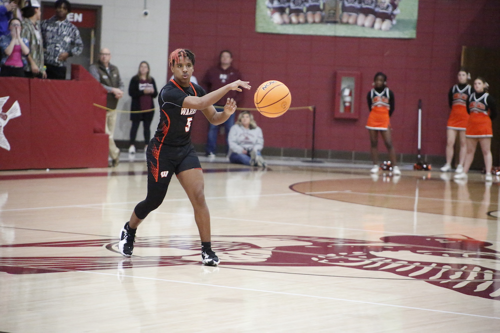 A person in black and red uniform playing basketball.