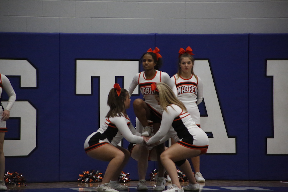A group of cheerleaders standing on top of a gym floor.