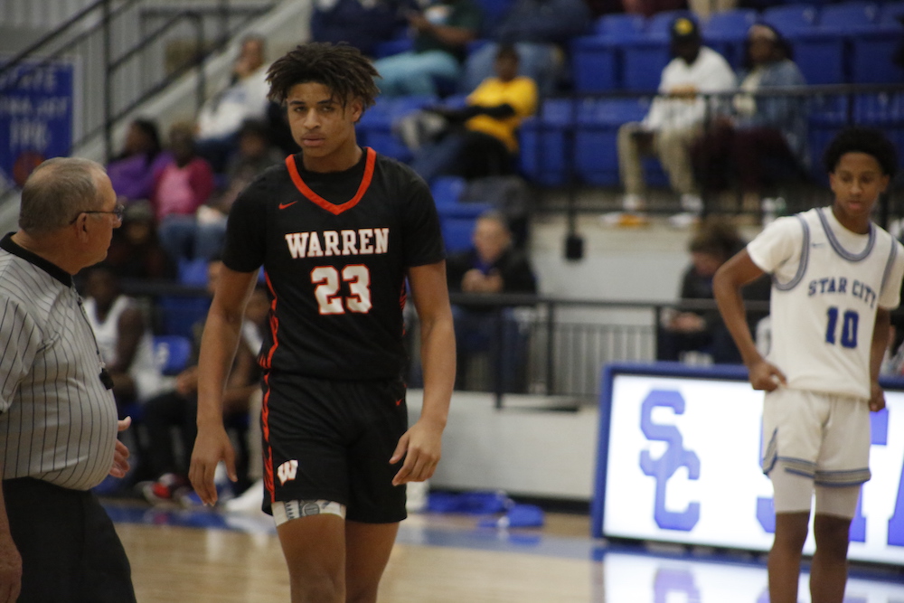 A young man in black shirt and shorts playing basketball.