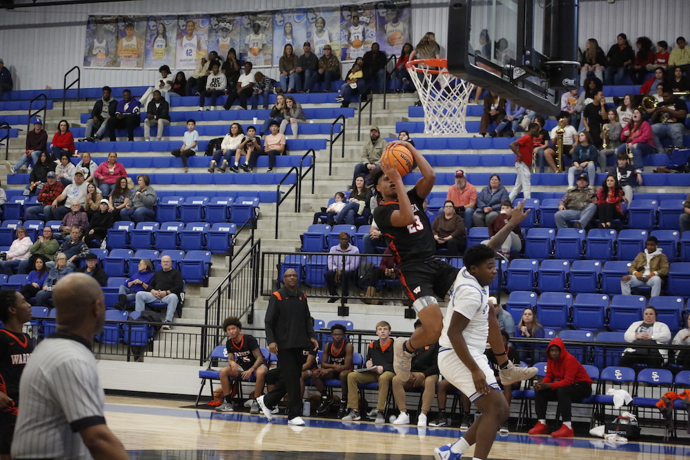 A basketball player is jumping in the air to dunk.