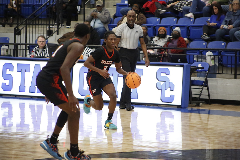 A couple of men playing basketball on a court.