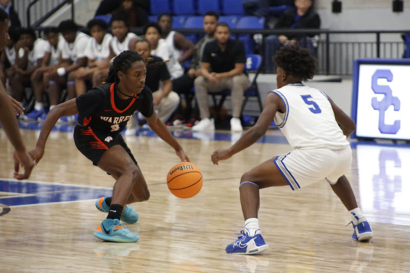 Two young men playing basketball on a court.
