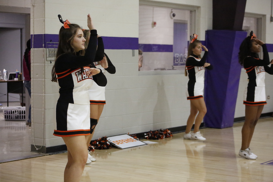A group of cheerleaders standing in front of a wall.