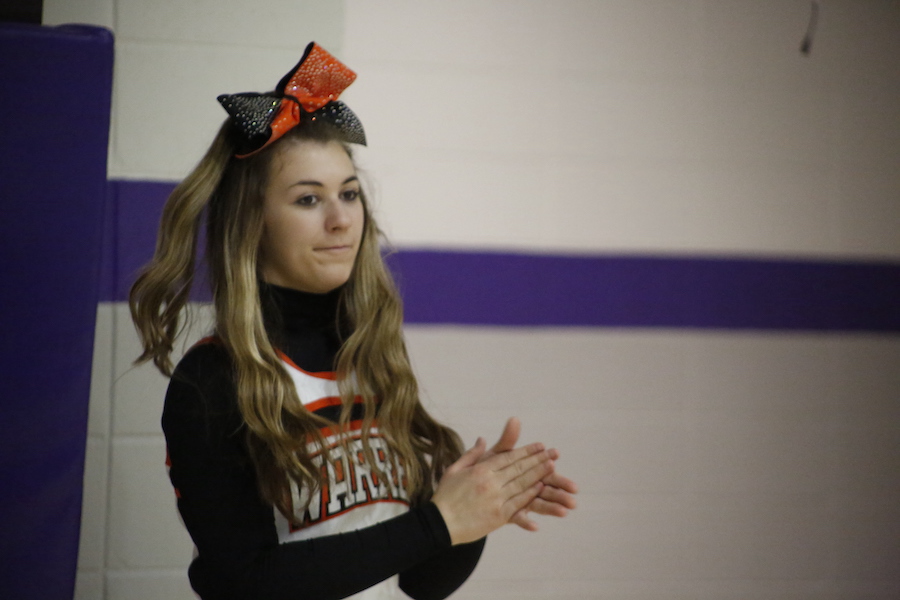 A cheerleader is clapping her hands in front of the camera.