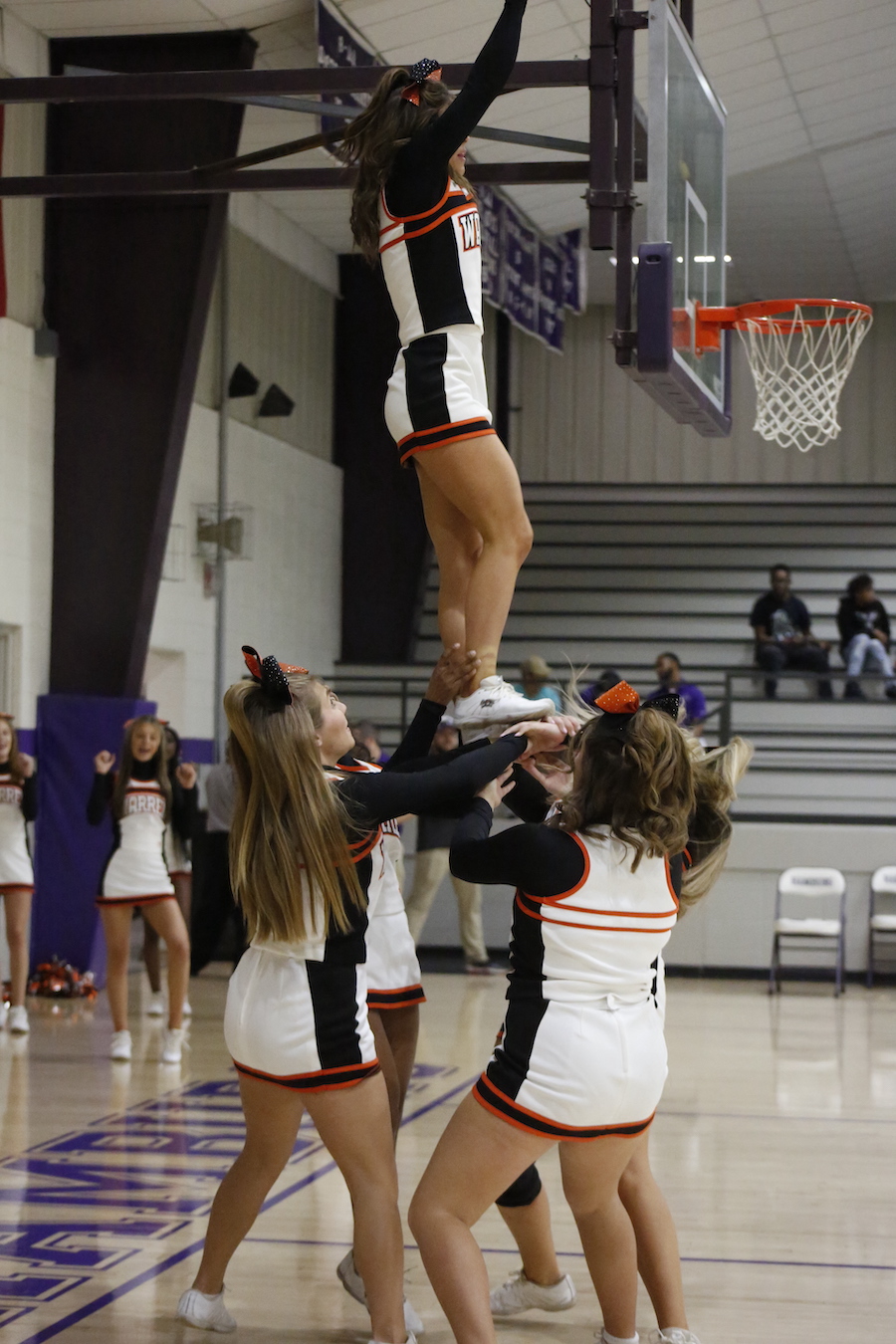 A group of cheerleaders are performing stunts on the court.