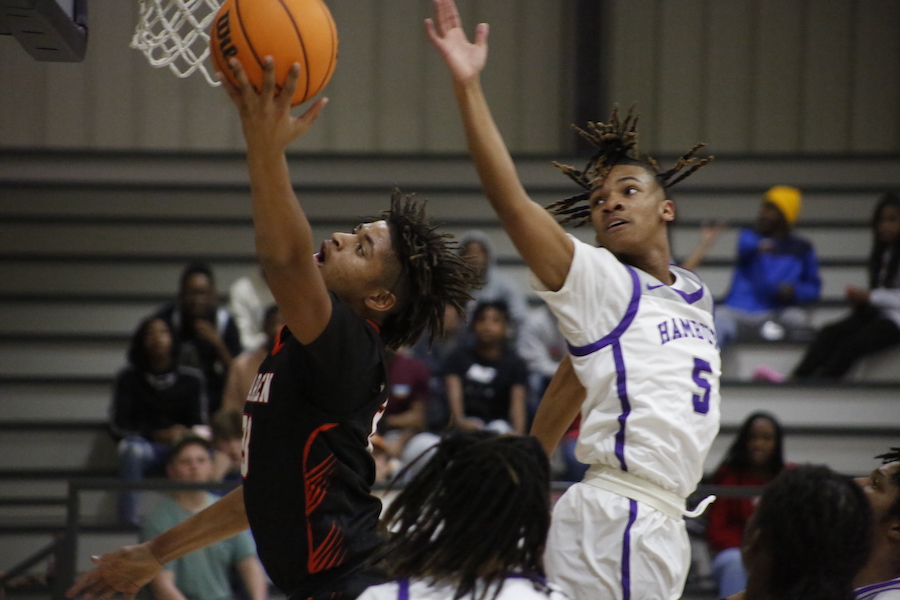 Two men playing basketball in front of a crowd.