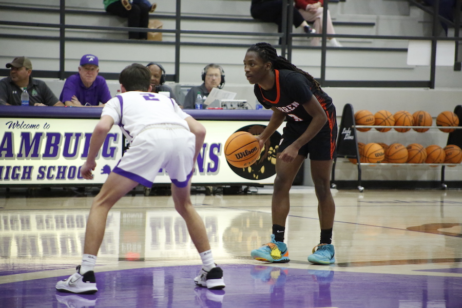 A basketball player is playing against another player.