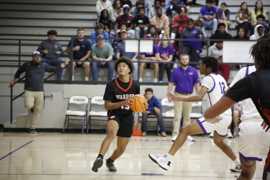 A group of people watching two men play basketball.
