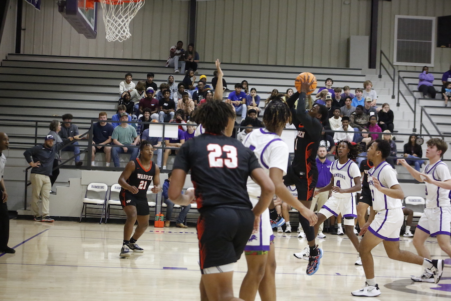 A group of people playing basketball in front of an audience.
