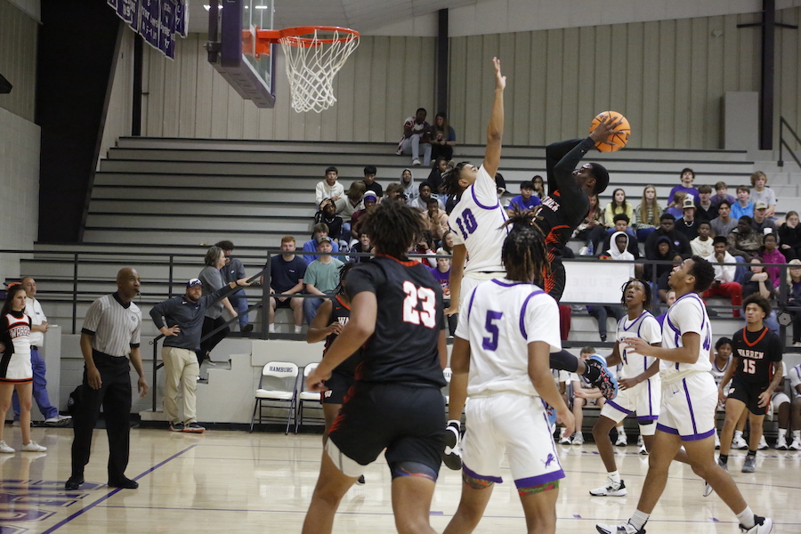 A group of people playing basketball in front of an audience.