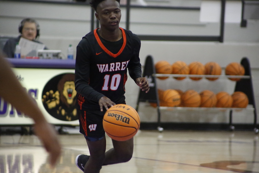 A man in black and orange jersey holding a basketball.