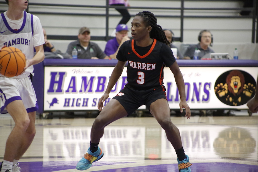 A woman in black and orange shirt playing basketball.