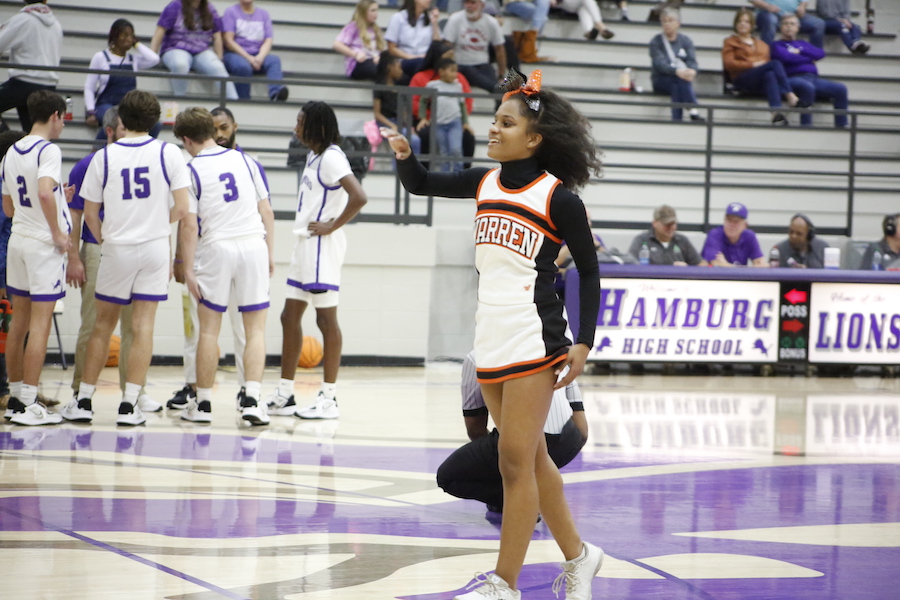 A girl in cheerleader uniform standing on the court.