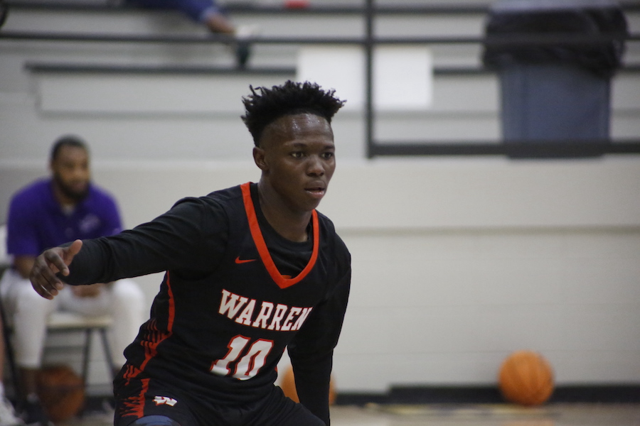 A young man in black and orange jersey playing basketball.