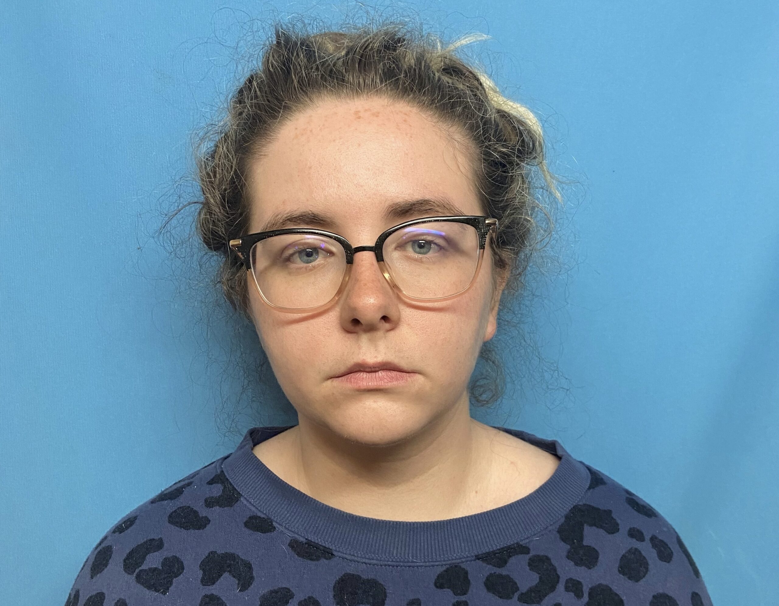 A woman with glasses and a leopard print shirt.
