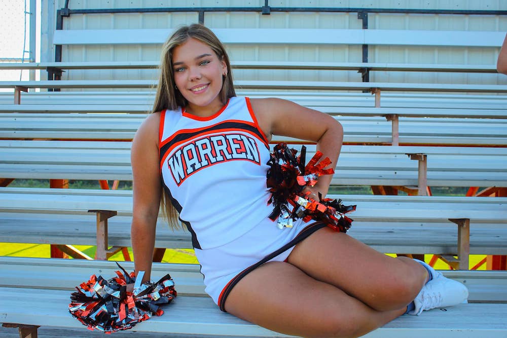 A girl sitting on the bleachers with her pom poms