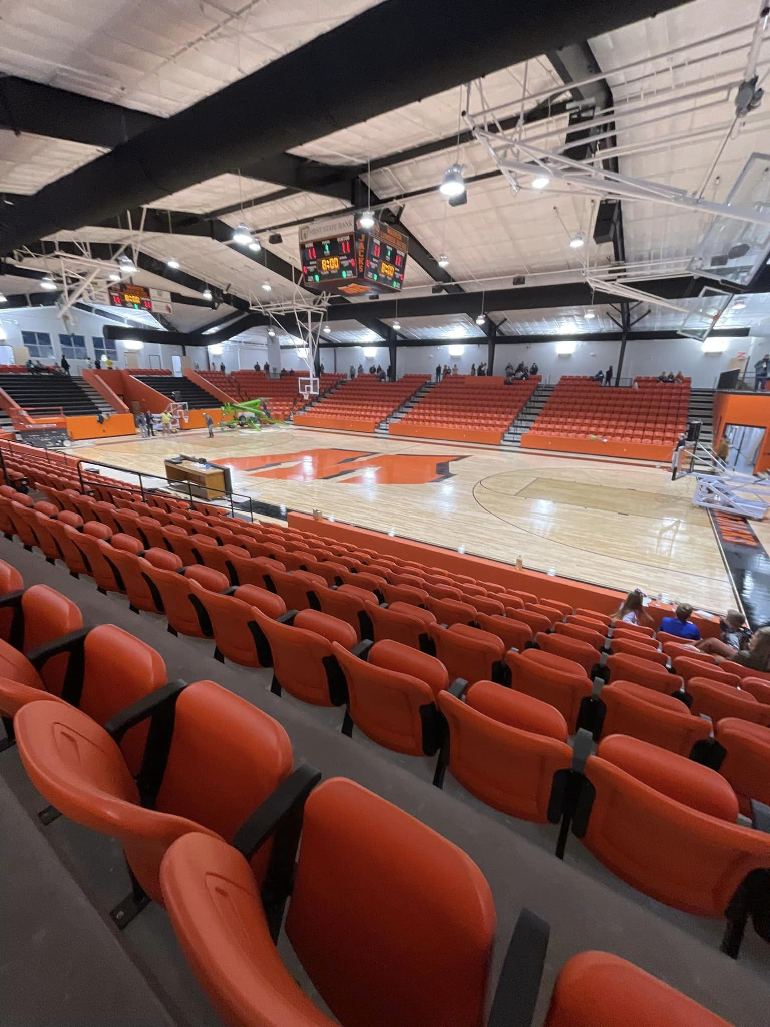 A large basketball arena with orange seats and lights.