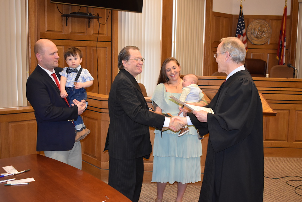 A judge and two men shaking hands in front of people.