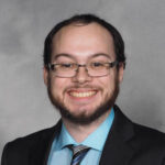 A man in a suit and tie smiling for the camera.
