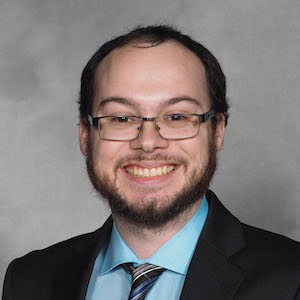 A man in a suit and tie smiling for the camera.