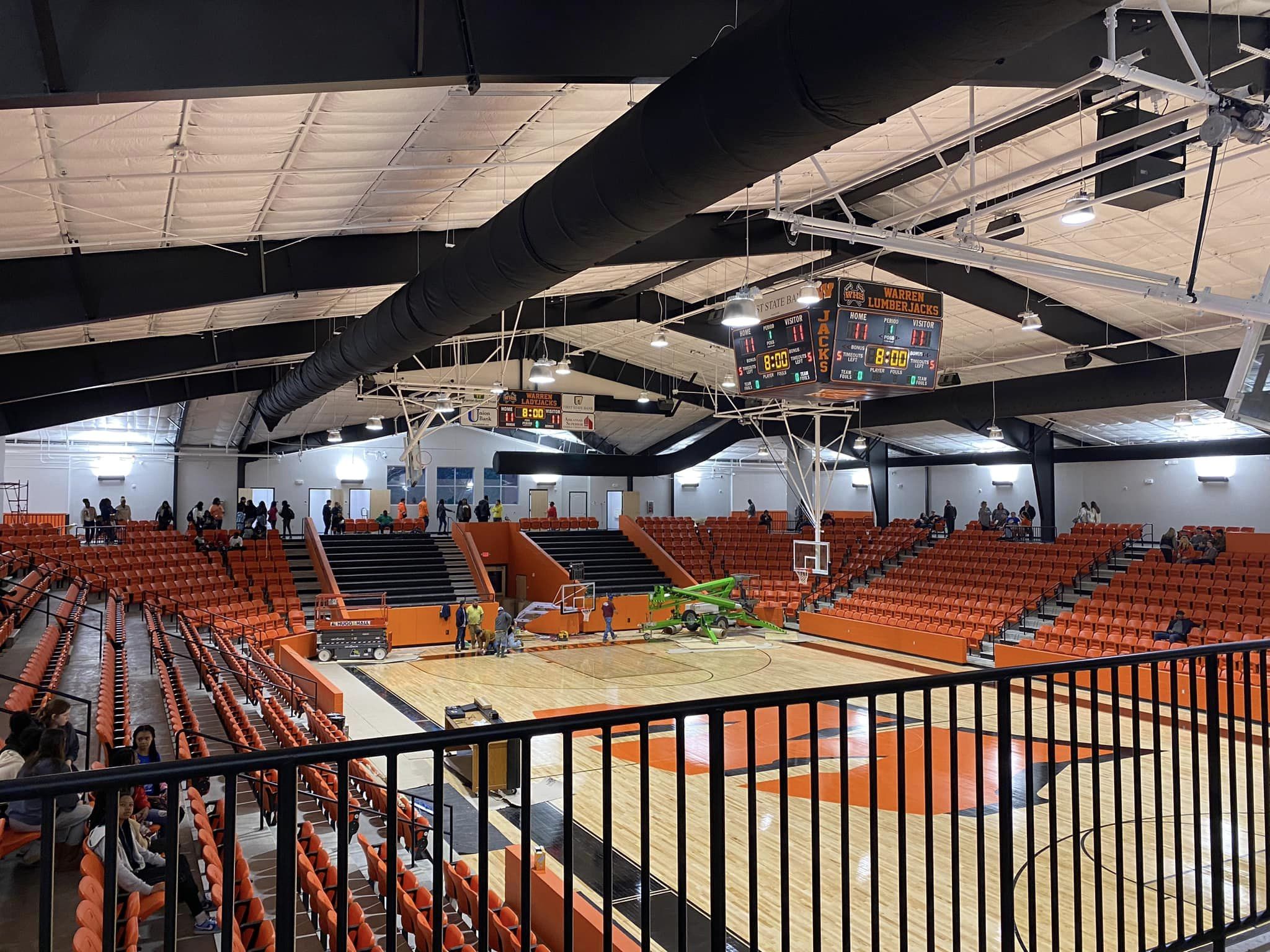 A basketball court with fans and lights in the middle.