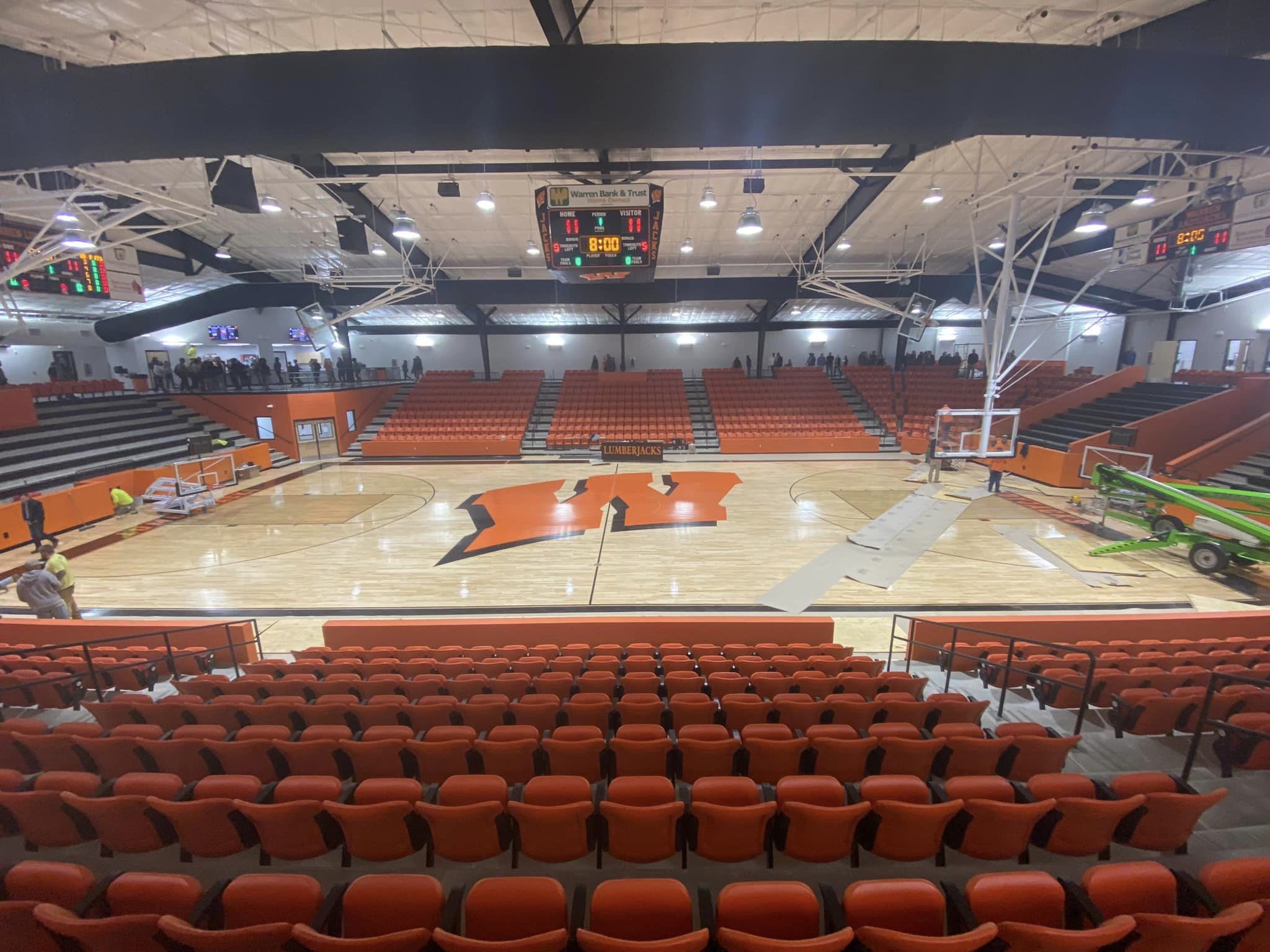 A large basketball court with orange seats and lights.