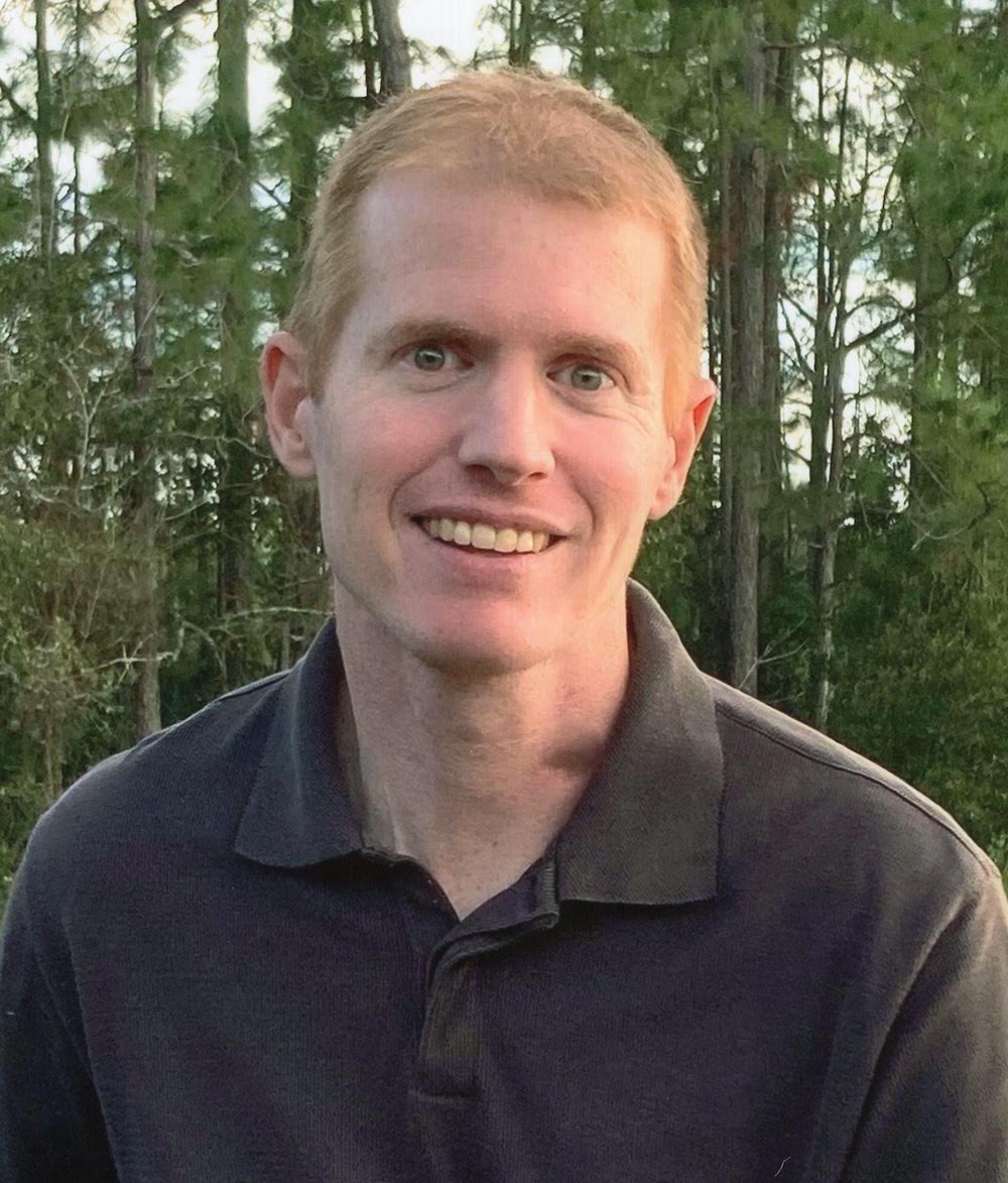A man with blonde hair and a black shirt.