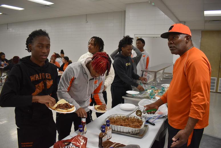 A group of people standing around a table with food.