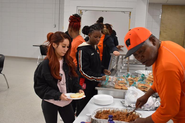 A group of people standing around a table with food.